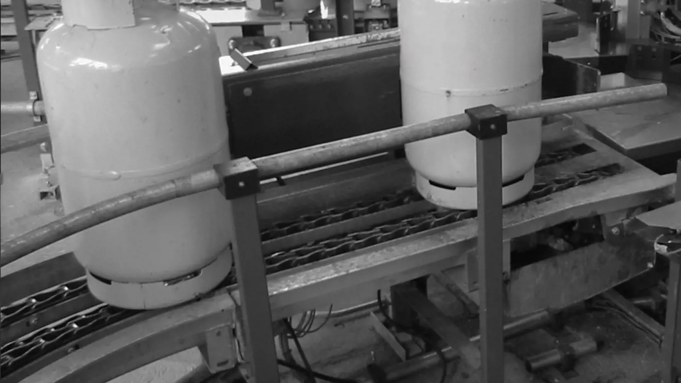 Chain conveyor Image of a chain conveyor with an LPG cylinder on it