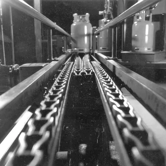 Wet chain conveyor Image of a wet dry conveyor chain with an LPG cylinder on it